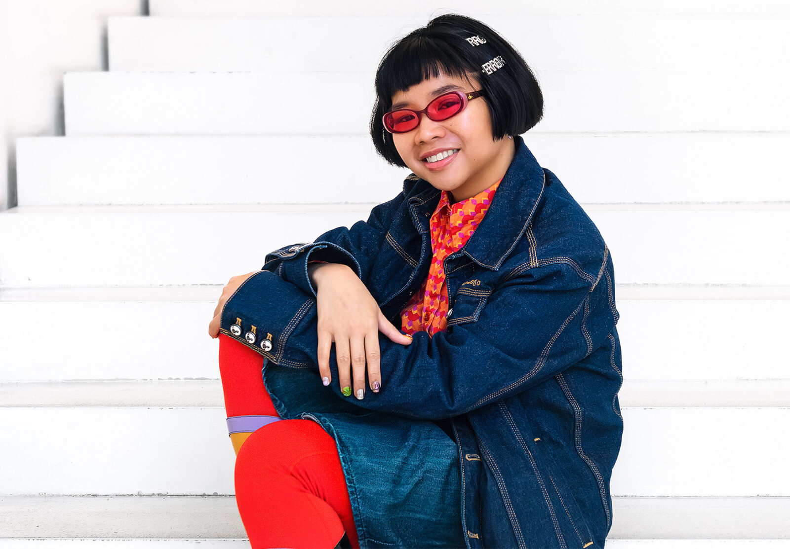 Taiteilija Natasha Tontey istuu Amos Rexin valkeassa portaikossa.ja hymyilee.