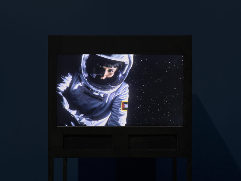 A person dressed in a spacesuit against a star-filled sky.
