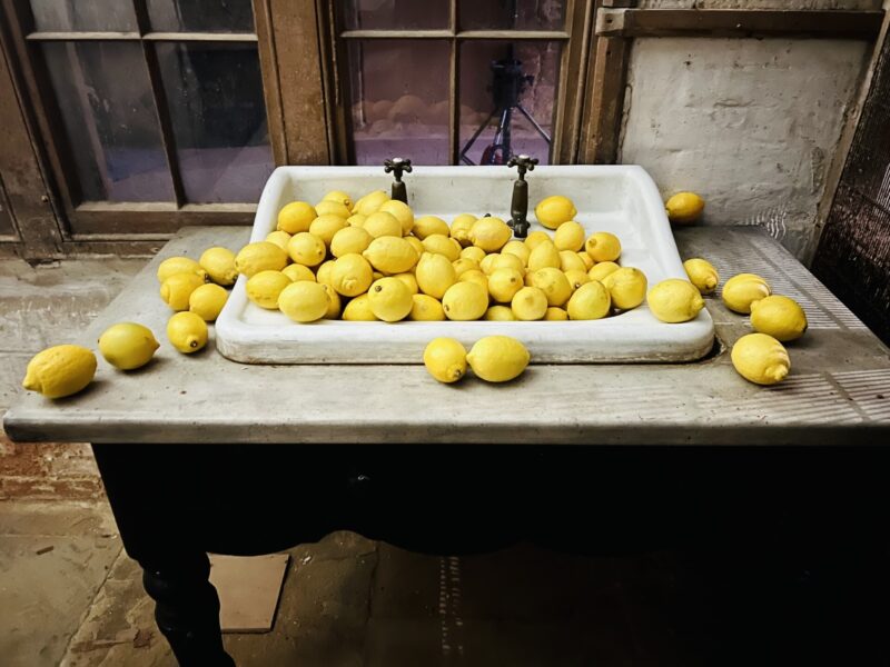 A sink on a table filled with lemons.