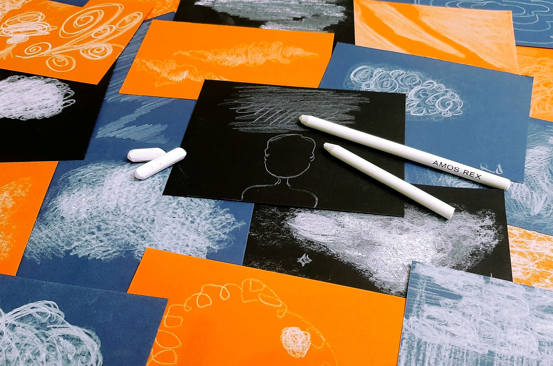 Oransseja, sinisiä ja mustia kortteja, joihin on piirretty valkeilla liiduilla.