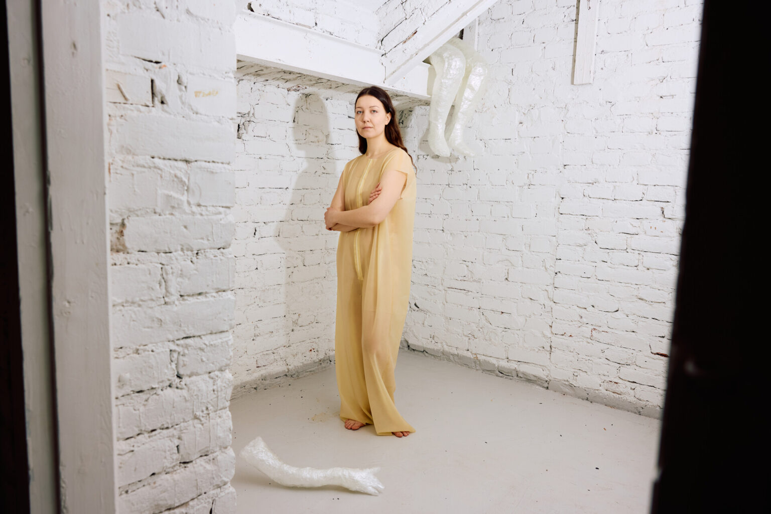 Stanislava Ovchinnikova står i en ljus klädsel i ett utrymme med vita tegelväggar.