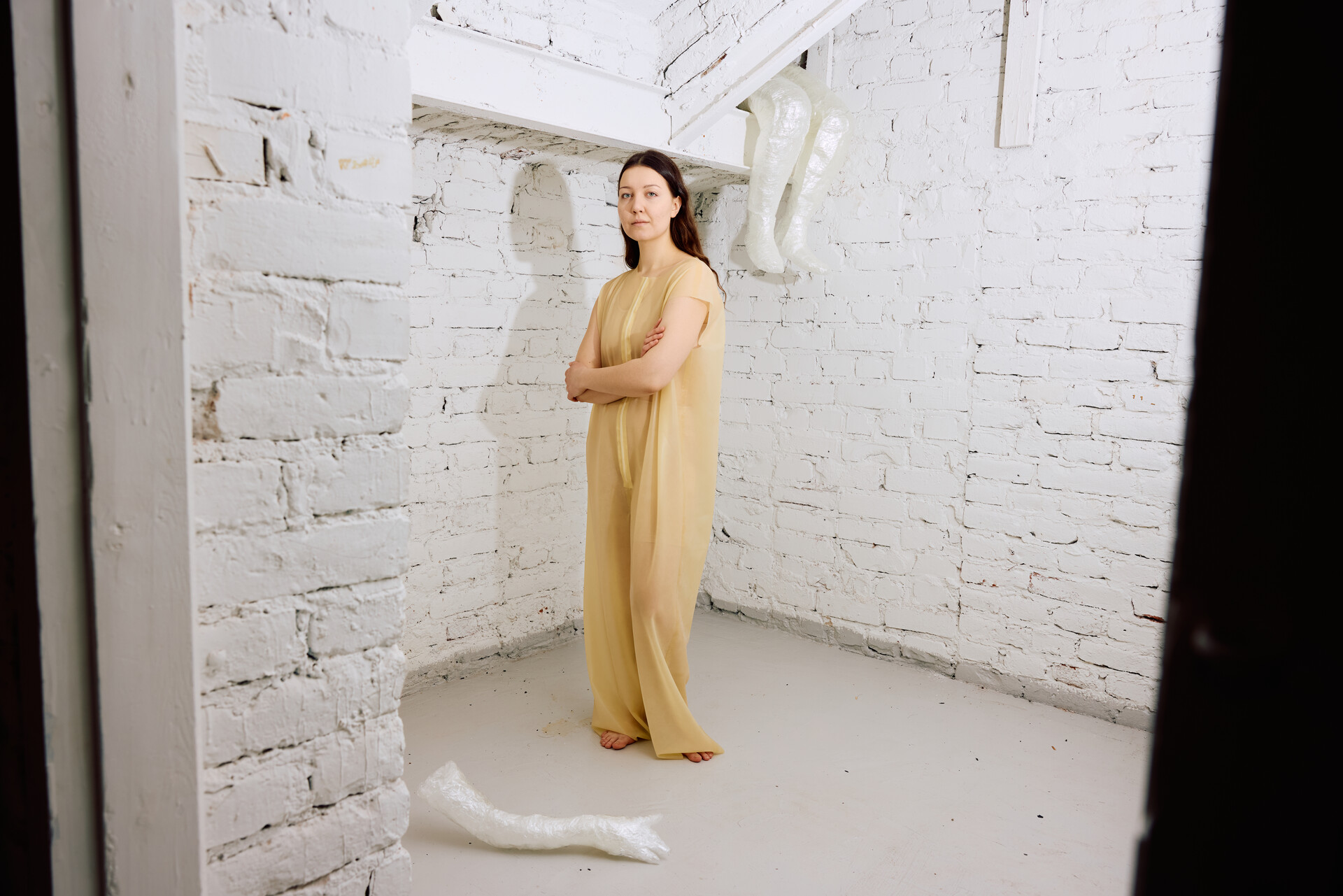 Stanislava Ovchinnikova seisoo vaaleassa asussa tilassa, jossa on valkoiset tiiliseinät.