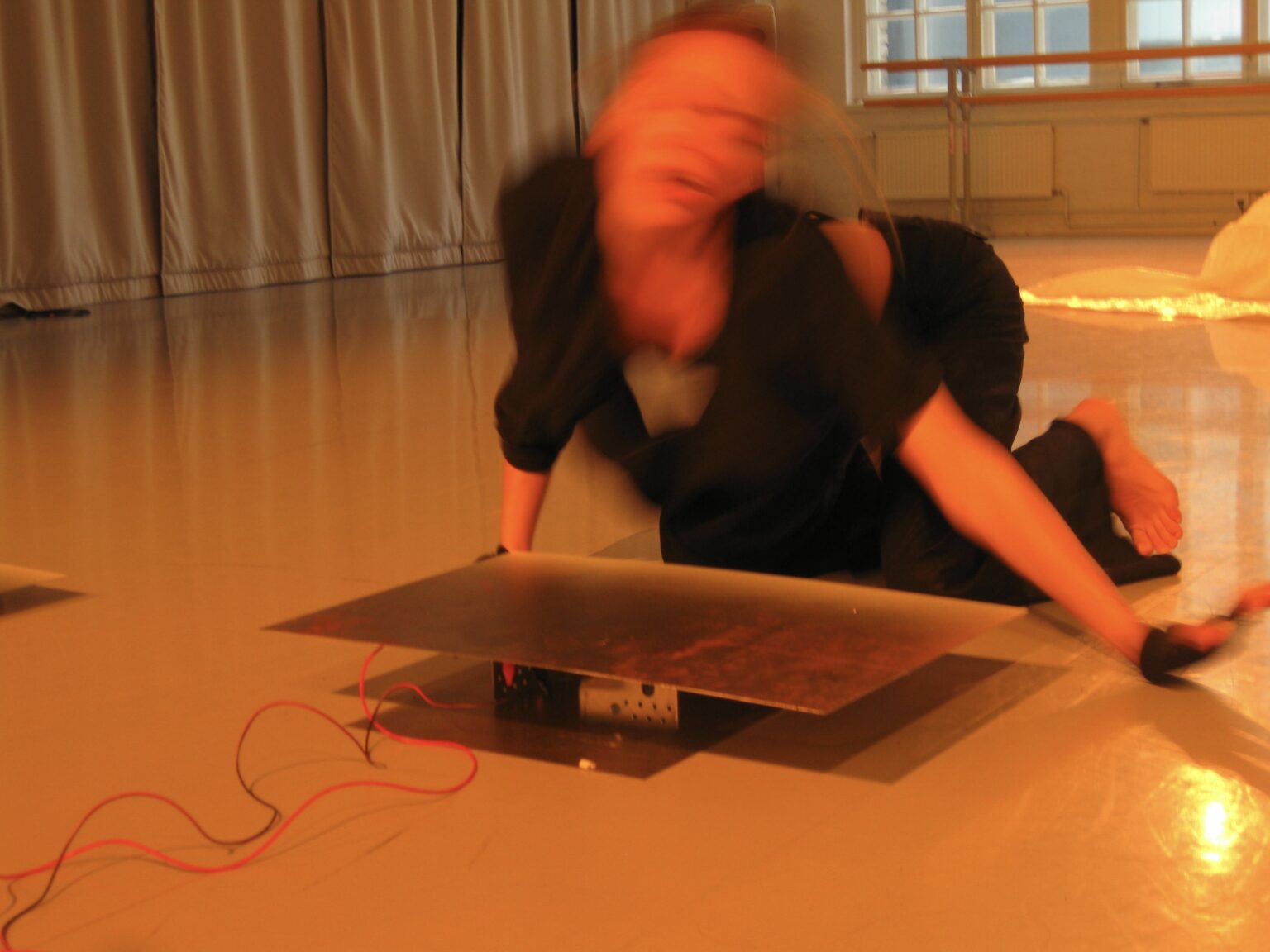 Lilja Kervinen rör sig på golvet i en dansstudio. Kervinen är klädd i svart och bilden är suddig på grund av rörelsen.