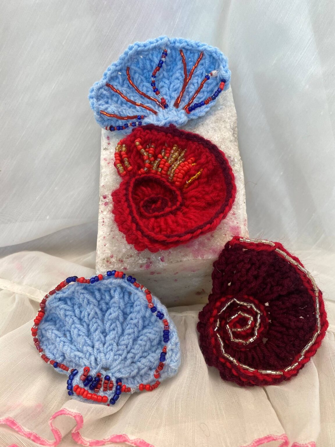 Several colourful crochet works on a white display.